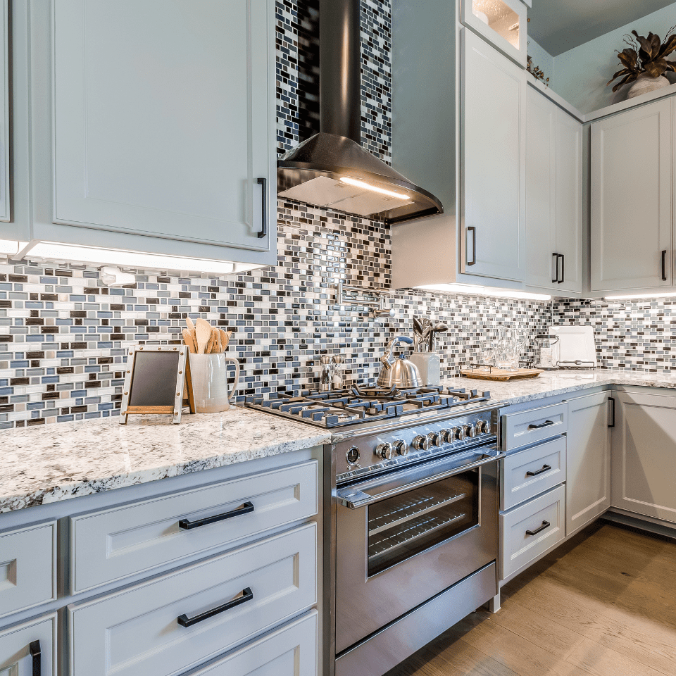 oven and range hood and countertops with under cabinet lighting 