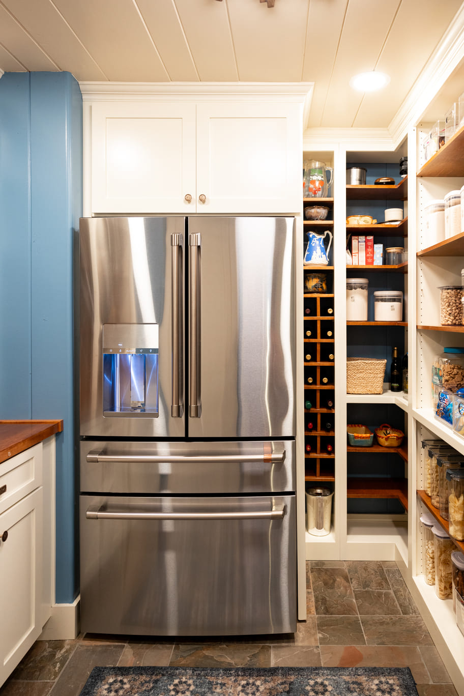 Refrigerator in kitchen with white custom shelving and storage areas with light blue walls