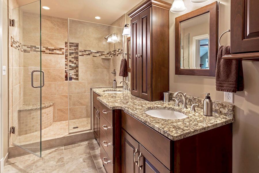Beautiful master bath remodel with tan finishings, dark wood cabinets and granite countertop
