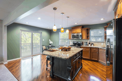 Kitchen upgrade with large marble island, wood flooring and natural light
