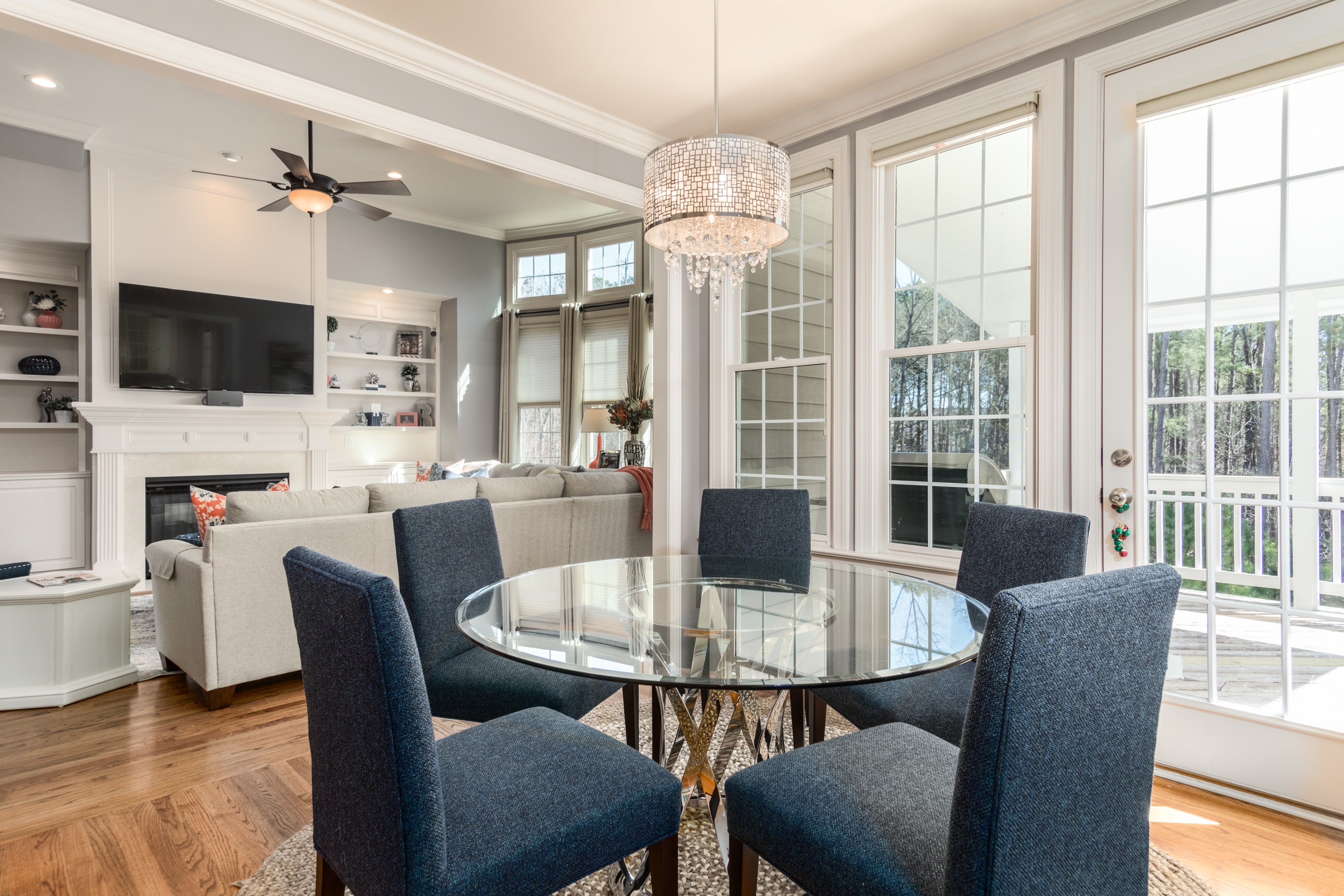 glass circle dining table with navy blue chairs in front of floor-to-cieling windows