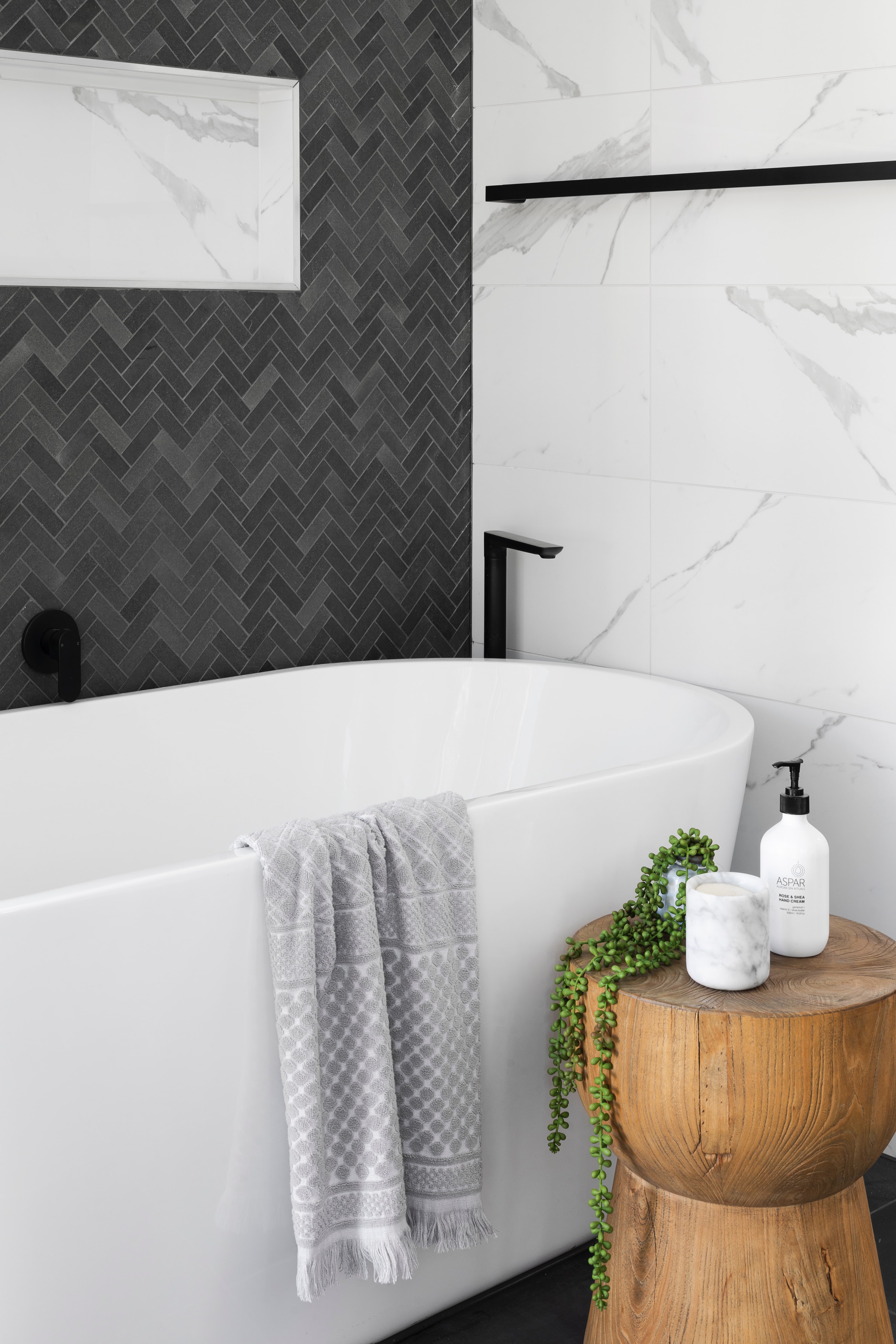white soaking tub with black herringbone accent wall in bathroom - Unsplash