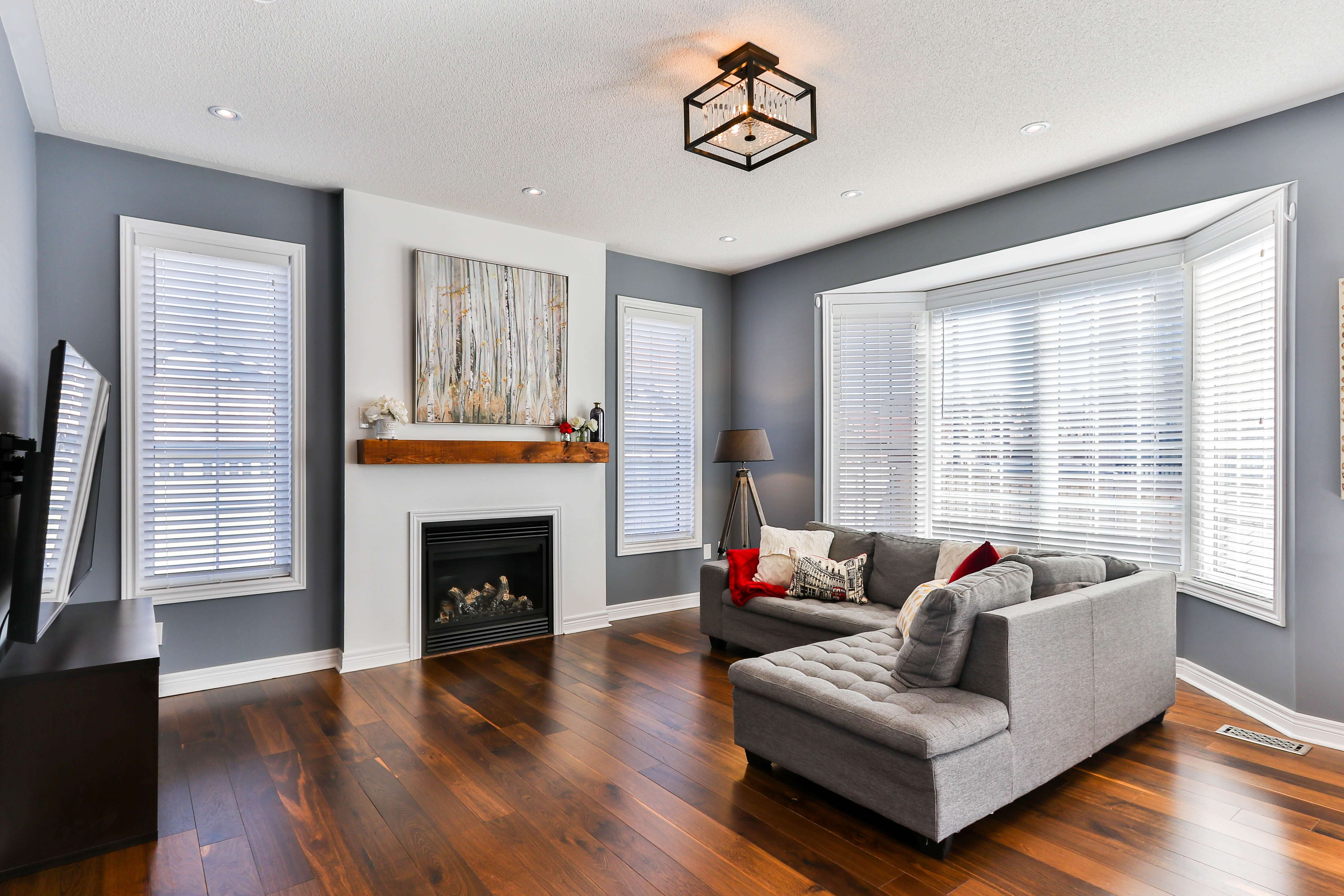 living room with dark hard wood floors, blue walls, white fireplace, & gray couch living room with dark hard wood floors, blue walls, white fireplace, & gray couch