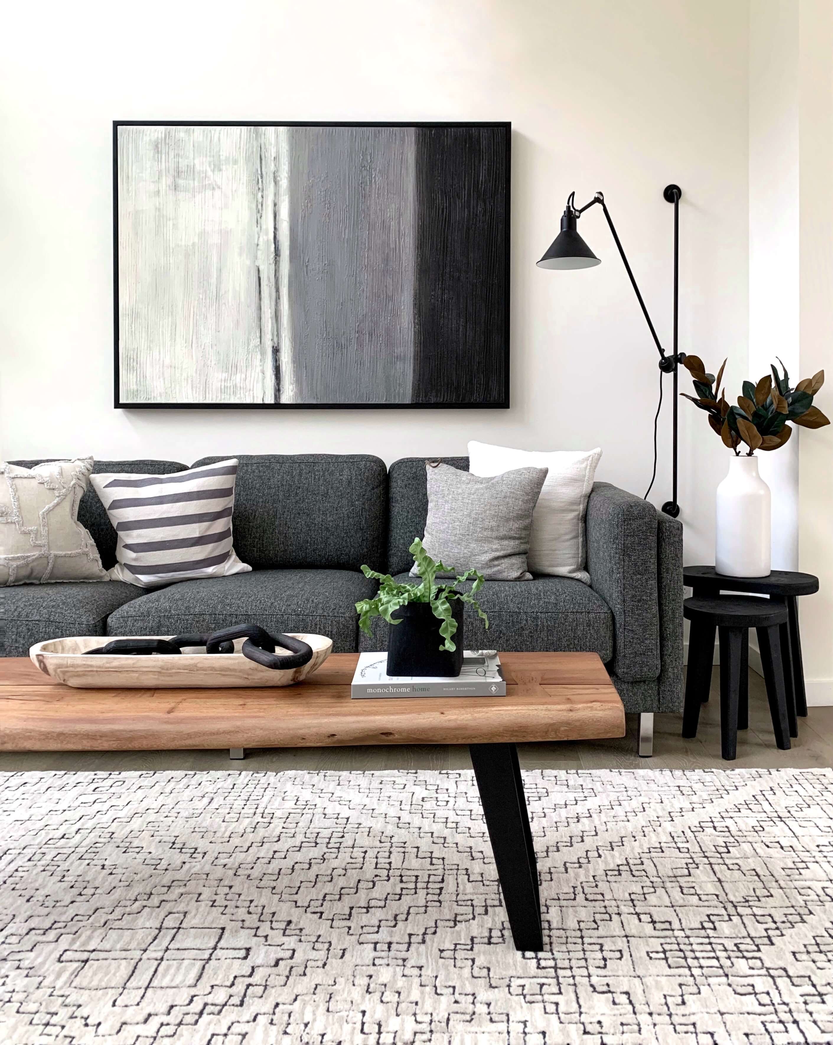 living room with wooden table, gray sofa couch, & abstractg painting on the wall living room with wooden table, gray sofa couch, & abstractg painting on the wall